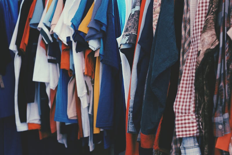 A rack of secondhand clothes on wooden hangers in a vintage shop.