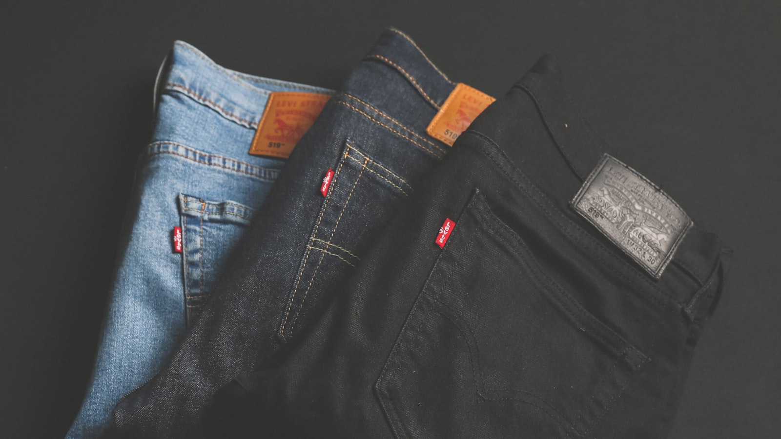 Several pairs of folded blue jeans stacked on a wooden surface.