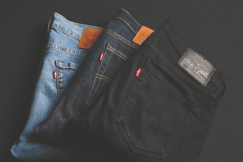 Several pairs of folded blue jeans stacked on a wooden surface.