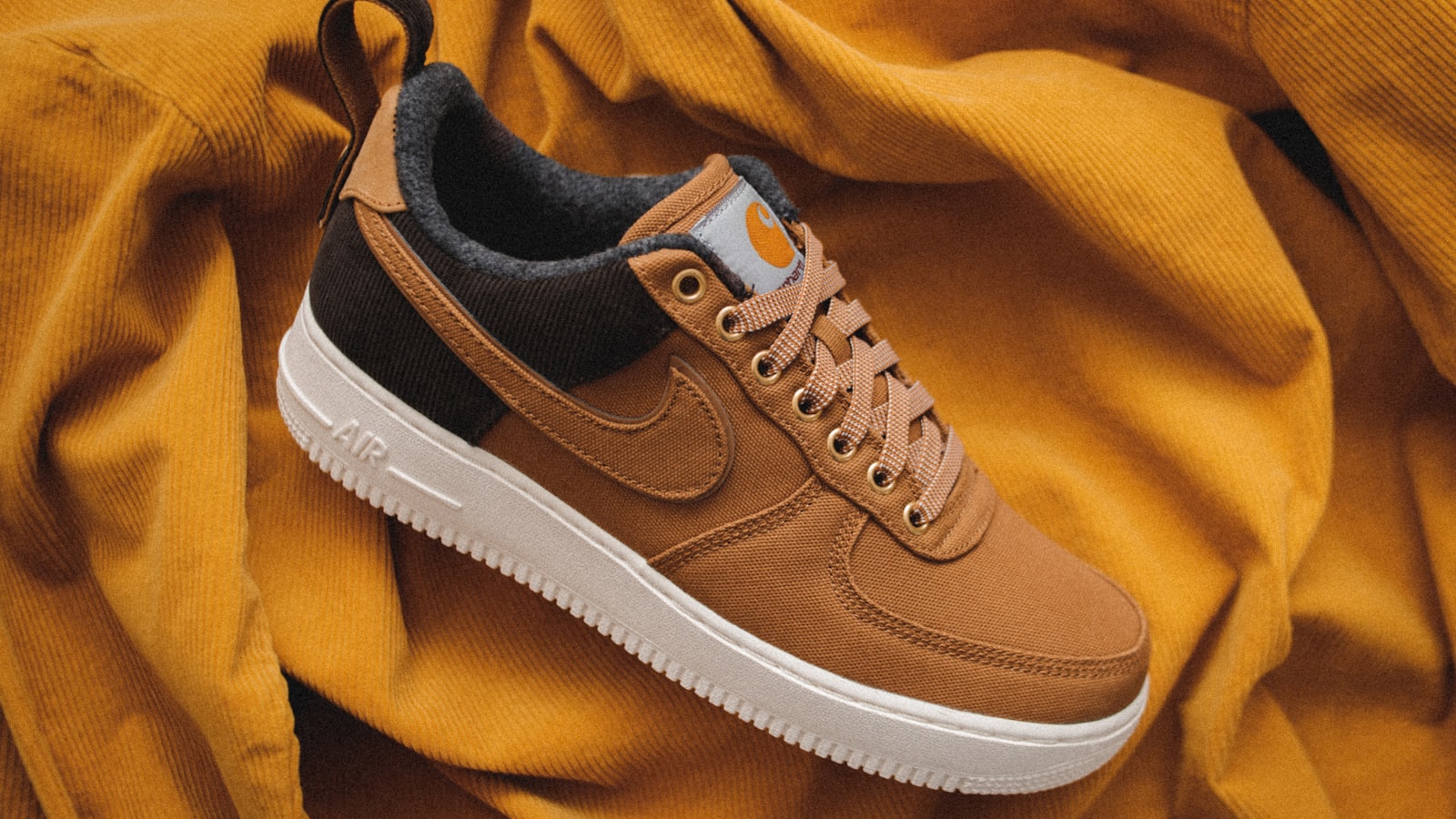 A pair of clean, simple leather sneakers in a neutral color on a plain floor.