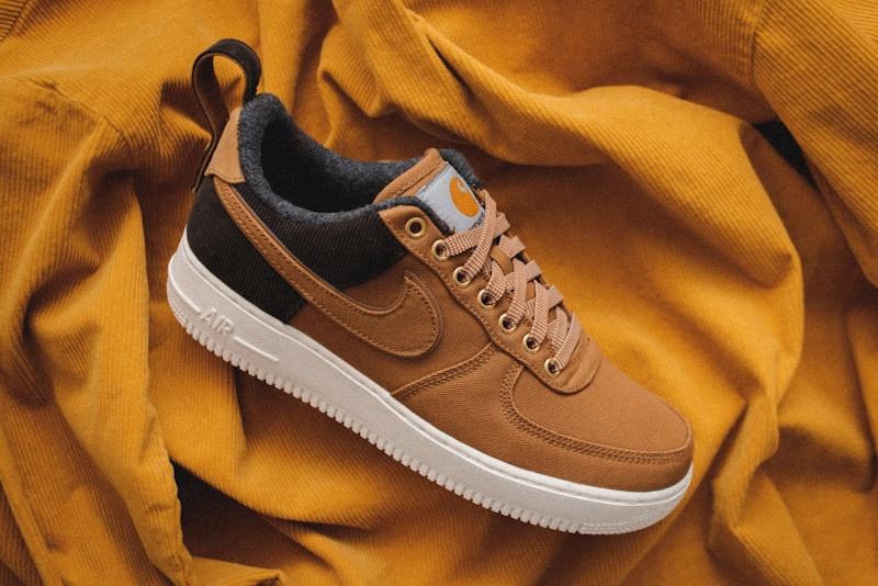 A pair of clean, simple leather sneakers in a neutral color on a plain floor.
