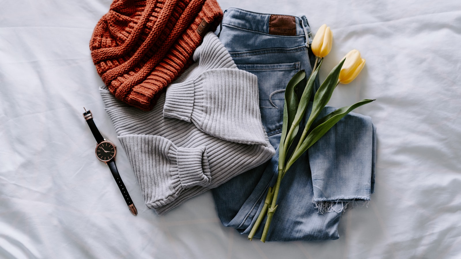 A neat stack of folded clothes and knitwear on a shelf.